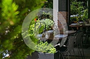 Street outdoor view of old fashion cozy cafe terrace with empty black chairs and tables