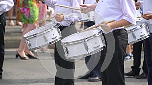 Street performance of festive march of drummers boys in costumes on city street. Close-up of boy`s hand drummers are