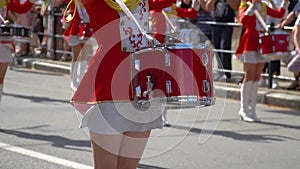 Street performance of festive march of drummers girls in red costumes on city street. Close-up of female hands drummers