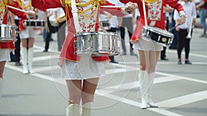 Street performance of festive march of drummers girls in red costumes on city street. Young girls drummer in red vintage