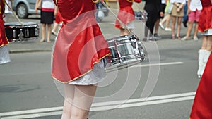 Street performance of festive march of drummers girls in red costumes on city street. Young girls drummer in red vintage