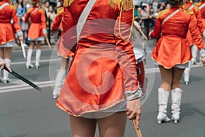 Street performance of festive march of drummers girls in red costumes on city street. Young girls drummer in red vintage