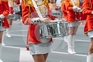 Street performance of festive march of drummers girls in red costumes on city street. Young girls drummer in red vintage