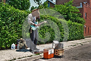 Street performer playing an electric guitar while wearing a horse head mask