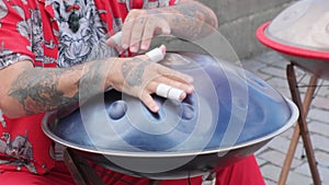 A of a street performer playing on the street, showcasing a performer with a handpan or hang.