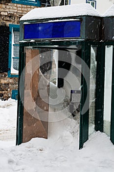 Street phone booth close-up completely covered with snow