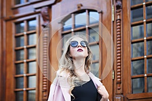 Street photo of beautiful young fashionable woman with sunglasses looking up. Female fashion. Closeup portrait