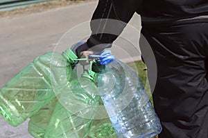 Street photo. Rear view of a man carrying several empty plastic bottles for drinking water.