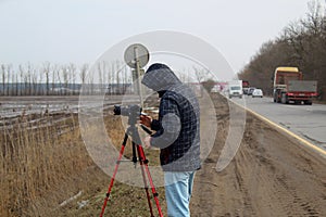 Street photographer in the process of shooting city landscapes. A camera on a tripod. A photographer in a jacket with a hood.