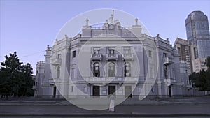 Street photographer in white dress. Young tourist woman taking picture of beautiful building back view. Girl taking a