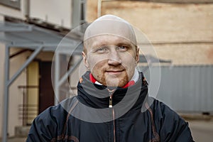 Street portrait of a Bald young man in his 30s looking straight at the camera and smiling. He may have undergone chemotherapy photo