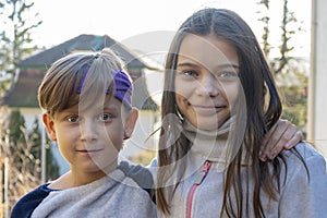 Street portrait of a boy and a girl on a neutral blurred background, brother and sister in an embrace.