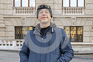 Street portrait of an elderly man 50-55 years old wearing a black hat and jacket.