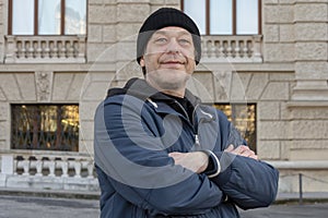 Street portrait of an elderly man 50-55 years old wearing a black hat and jacket.