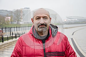 Street portrait of an elderly man, about 50, bald with a beard. Life-affirming look, self-confidence. The profession of driver