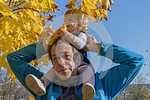 Street portrait of an elderly man holding a little girl on his shoulders. Concept: children and parents, paternal care of the daug