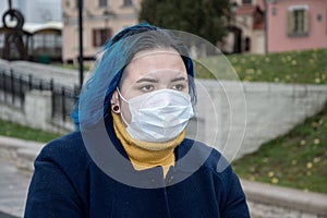 Street portrait of a girl 20-25 years old in a medical mask on her face. Risk of virus infection. Precautions, prevention of disea