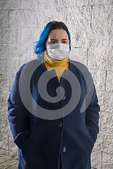 Street portrait of a girl 20-25 years old in a medical mask on her face. Risk of virus infection. Precautions, prevention of disea photo