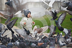 Street portrait of the little boy feeding pigeons with bread