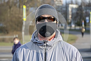 Street portrait of a man of 30-35 years of Eastern appearance in a black medical mask and dark glasses.