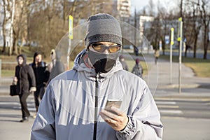 Street portrait of a man of 30-35 years of Eastern appearance in a black medical mask and dark glasses on the street looking