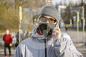 Street portrait of a man of 30-35 years of Eastern appearance in a black medical mask and dark glasses, talking on the street