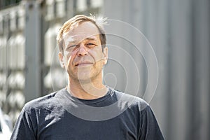 Street portrait of a man 40-50 years old in a black t-shirt on a neutral blurred background. Perhaps he is just a buyer, an actor