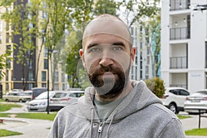 Street portrait of a serious man 30-35 years old with a beard on the background of beautiful high - rise   buildings.