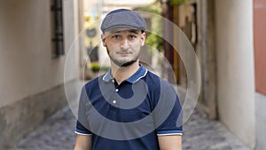Street portrait of a serious young man 30 -35 years old in a cap with a beard looking directly into the camera on a neutral backgr