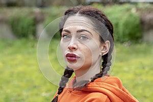 Street portrait of a woman 25-30 years old against the background of nature.