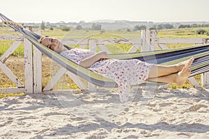 Street portrait of a woman 35-40 years old, relaxing in nature in a hammock with a neutral background, Concept: outdoor recreation