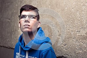 Street portrait of young boy in blue sweatshirt with modern eyeglasses
