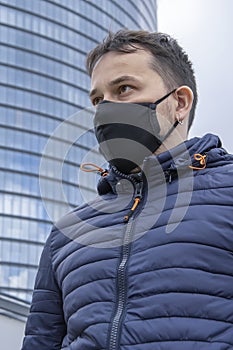 Street portrait of a young man in a medical mask on the background of an urban landscape.Concept:health care, life in a smoke-