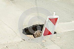 Street reconstruction or construction barricade traffic danger caution sign cover the open hole of damaged and cracked asphalt on