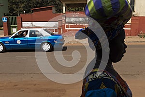 Street scene in the city of Bissau with the silhouette of a woman and a taxi on the background, in Guinea-Bissau.