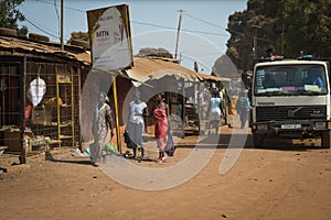 Street scene in the city of Bissau with women waling along a dirt road, in Guinea-Bissau