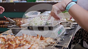 Street Seller Weighs Salads in a Lunch Box on an Electronic Scale. Zoom