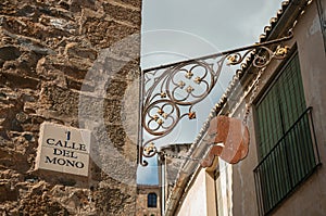 Street sign in ceramic tile and artistic iron sculpture at Caceres