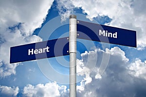 Street sign in front of cloudy sky representing choice between listening to the â€˜heartâ€™ or the â€˜mind`