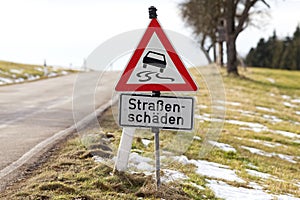 Street sign in germany warning Slippery road water, ice, snow, oil or dirt - text translation `damaged street`