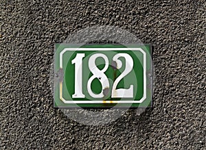 Street sign number 182 on a gray wall