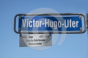 Street sign Victor Hugo Ufer - english: Victor Hugo riverbank - under clear blue sky