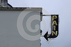 Street sign with the word pain on it against cloudy grey sky and background in France. In French language the word means bread.