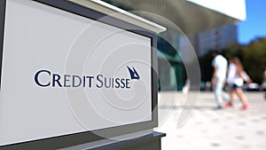 Street signage board with Credit Suisse Group logo. Blurred office center and walking people background. Editorial 3D