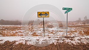 Street signs and arrows sign - cross-section of two rural gravel roads in Northern Wisconsin - cold snowy winter day in the gras