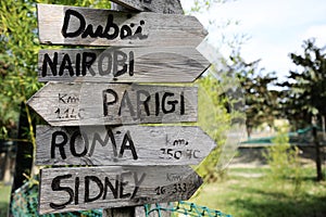 Street signs in the natural park indicating directions to different places of the world. Green plants on the background.