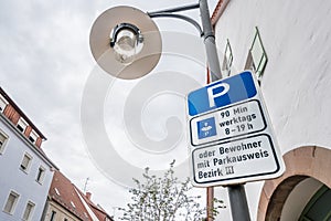 Street signs with street lamp in Germany saying parking 90 minutes weekdays 8am - 7pm or residents with parking permit district 3