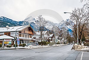 street of a small Alpine town and ski resort with typical houses, road and mountains