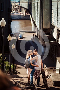 Street sport and hobby concept. Vertical shot of lovely couple of skaters have break after skating, embrace and going to