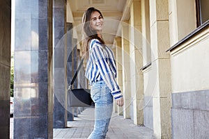 Street Style Outdoors Portrait of Beautiful Girl. Fashion Woman Smiling. She wearing Print Shirt, Jeans, Bag. Lifestyle